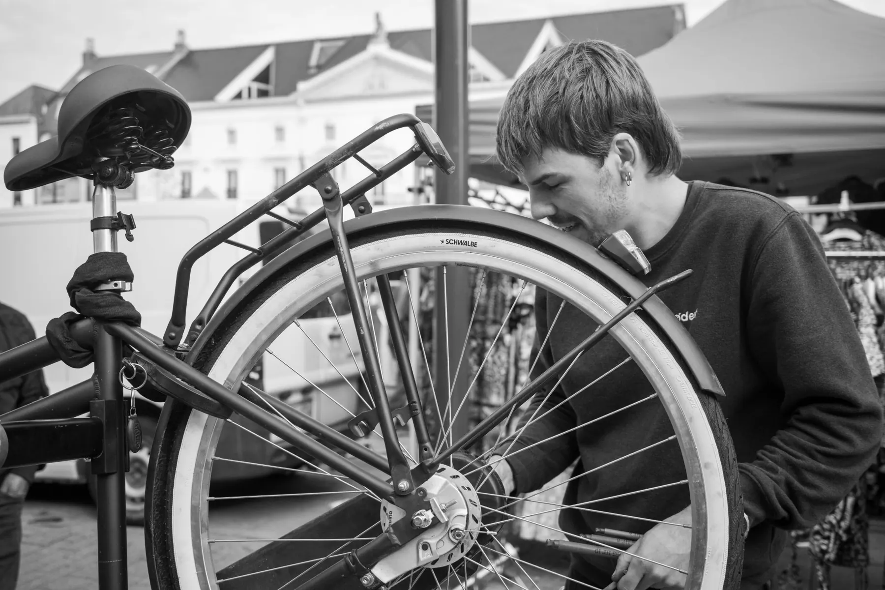 Nathan herstelt een achterwiel aan zijn kraam op de markt